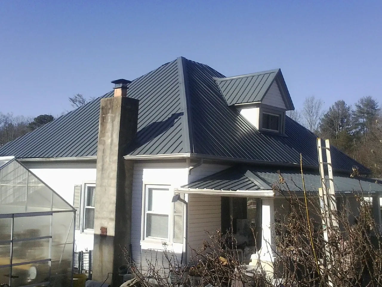 Dark blue standing seam metal roof on a white farmhouse with dormer — Slate & Tile Roof Repair by Roofing Brothers in Rimersburg