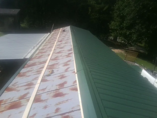Old rusted panels beside newly installed green metal roofing — Wind Damage Roof Repair by Roofing Brothers in Rimersburg