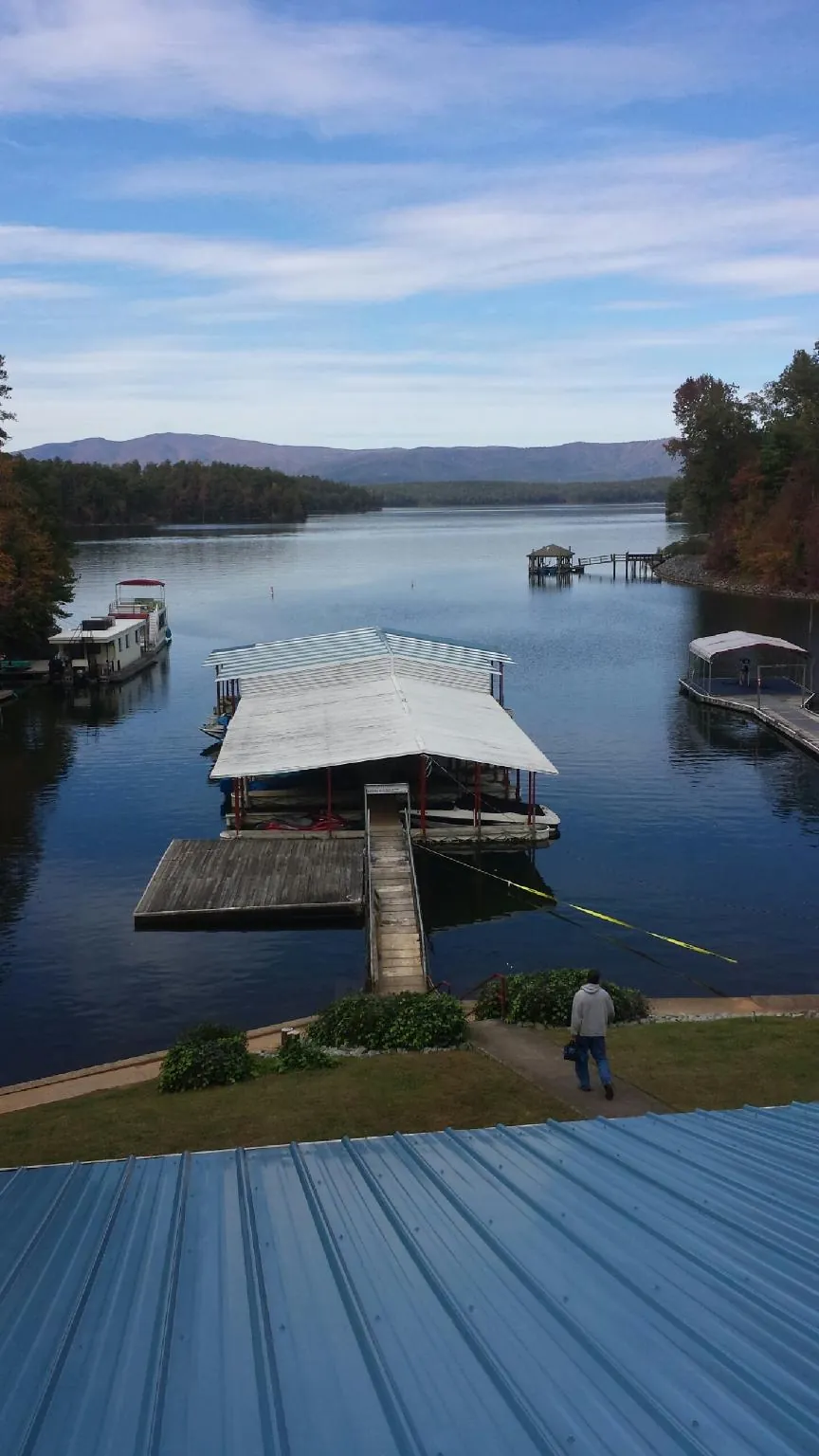 View across a lake from a newly installed blue metal roof in Rimersburg