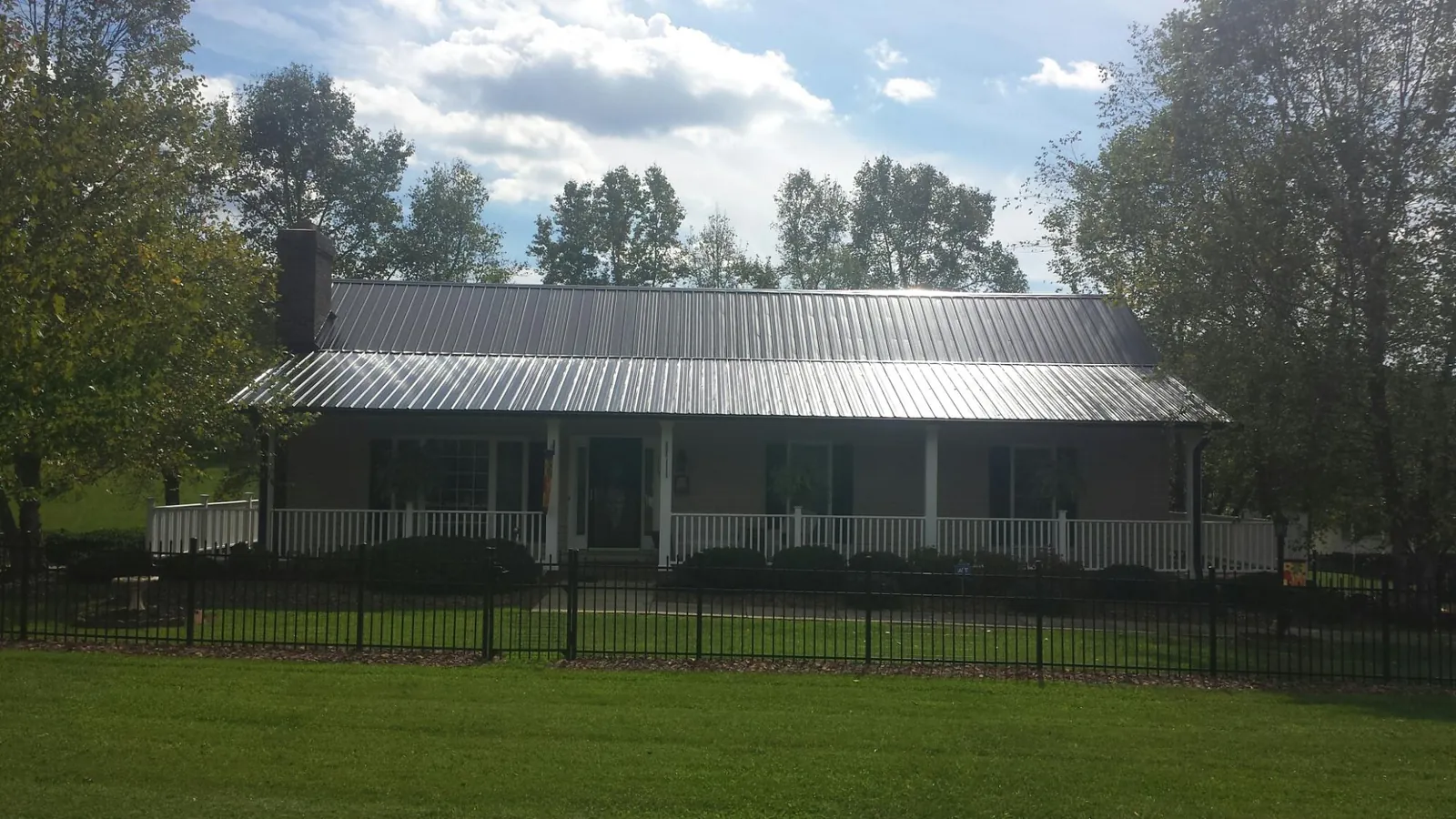 Gray metal roof on a brick ranch with a full width front porch — Gutter Guard Installation work by our crew in Rimersburg