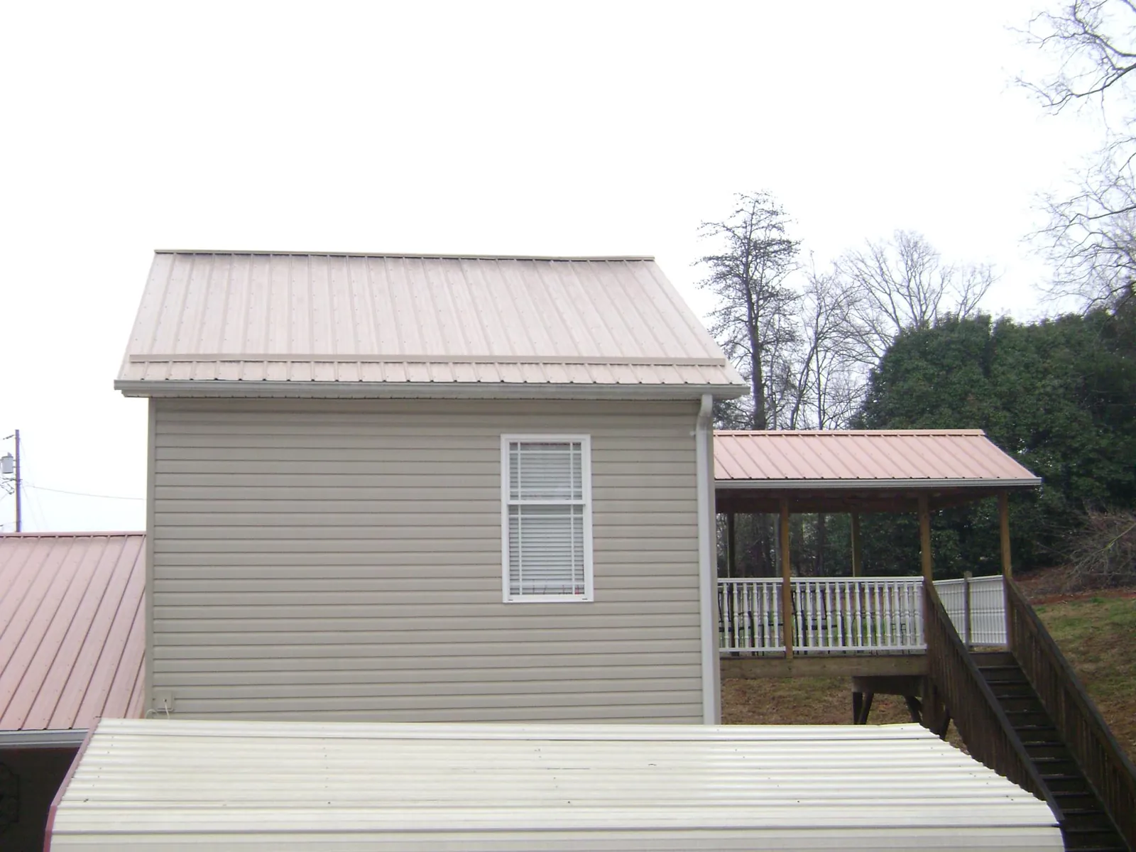 Tan metal roofs on a two story addition and attached porch, from a Roof Replacement job in Rimersburg