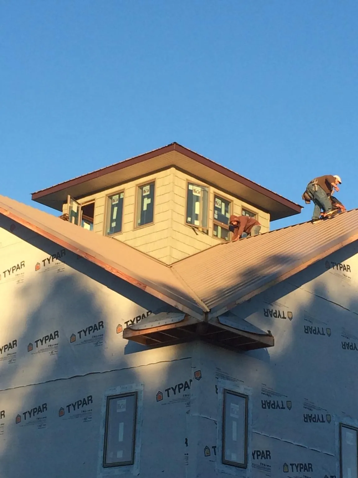 Roofers working around a rooftop cupola on a new metal roof at sunset — Roof Waterproofing in Rimersburg by Roofing Brothers